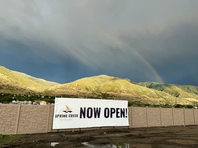 Rainbow over the Wasatch mountains above the Spring Creek RV Resort Now Open banner