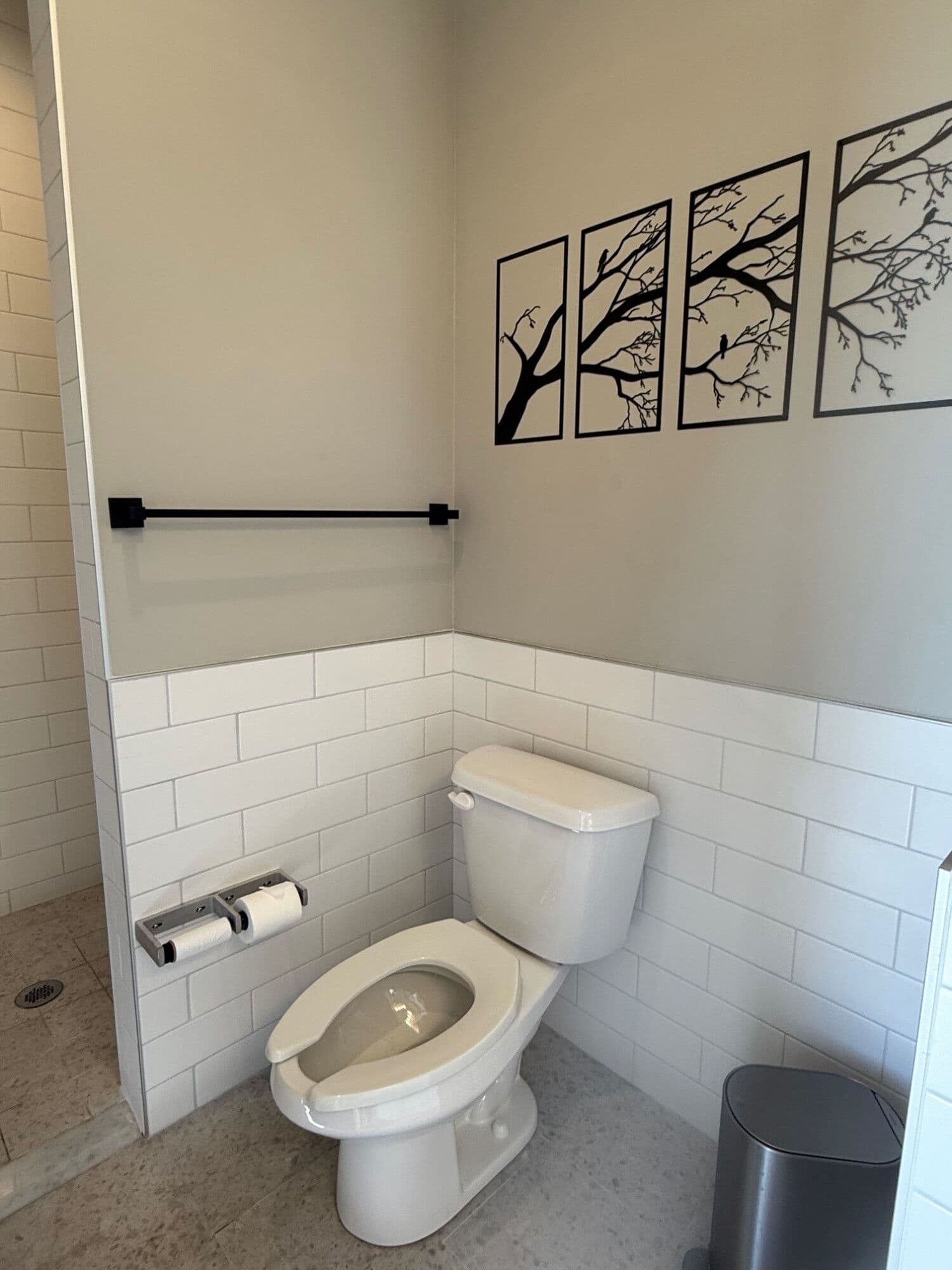 Private restroom with subway tile wainscoting and tree branch wall art